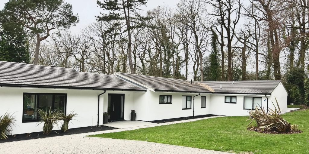 Rendered white bungalow set among mature trees
